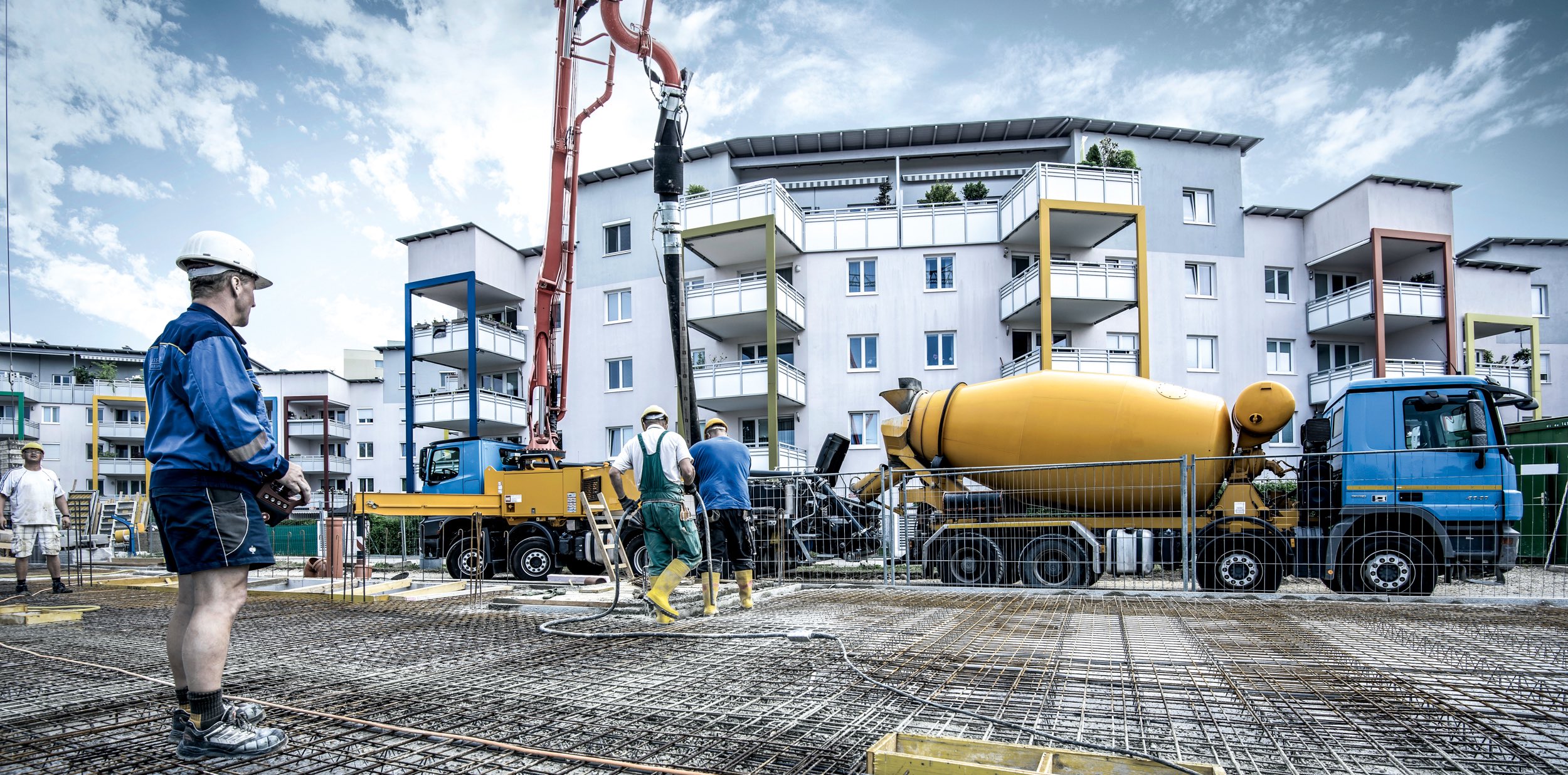 Betonpumpe fördert Transportbeton auf eine Baustelle, auf der eine Fundamentplatte betoniert wird